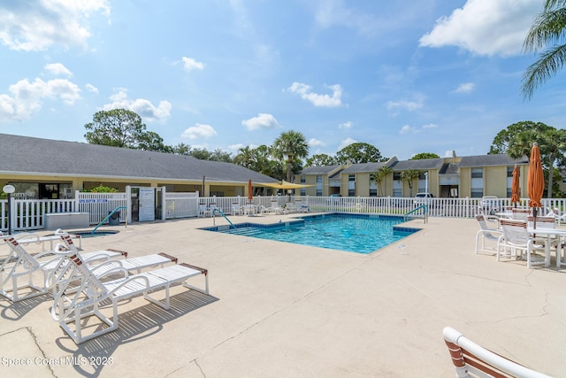 community pool with a patio area and fence