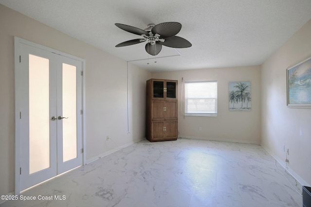 unfurnished bedroom featuring marble finish floor, baseboards, a textured ceiling, and french doors