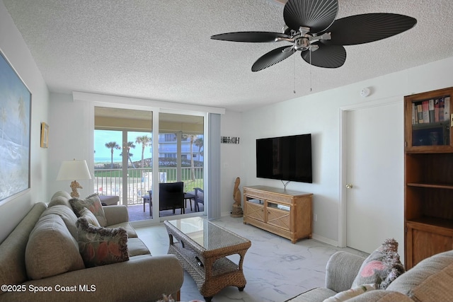 living room featuring a ceiling fan, expansive windows, marble finish floor, and a textured ceiling