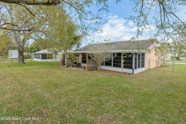 rear view of property featuring a sunroom, stucco siding, a lawn, and fence