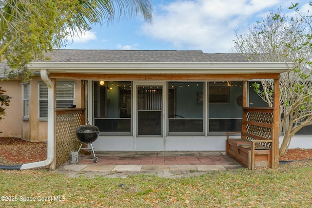 back of property featuring roof with shingles, a sunroom, and stucco siding