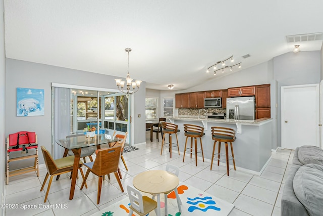 dining area featuring light tile patterned floors, baseboards, visible vents, vaulted ceiling, and a chandelier