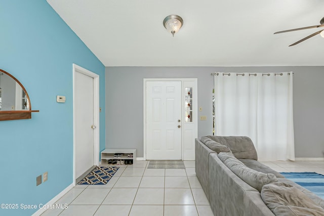 interior space featuring lofted ceiling, light tile patterned flooring, a ceiling fan, and baseboards