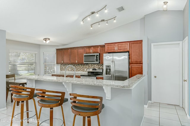 kitchen featuring light tile patterned floors, tasteful backsplash, visible vents, lofted ceiling, and stainless steel appliances