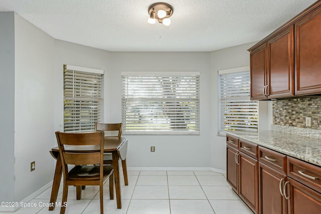 dining area with light tile patterned floors, baseboards, and a textured ceiling