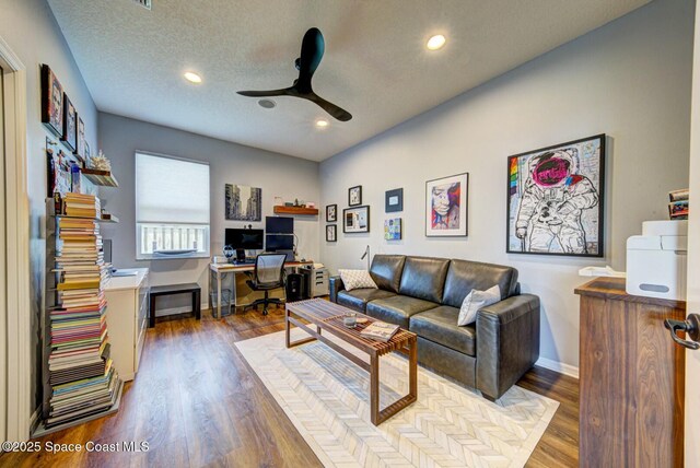 living area featuring baseboards, a ceiling fan, wood finished floors, a textured ceiling, and recessed lighting