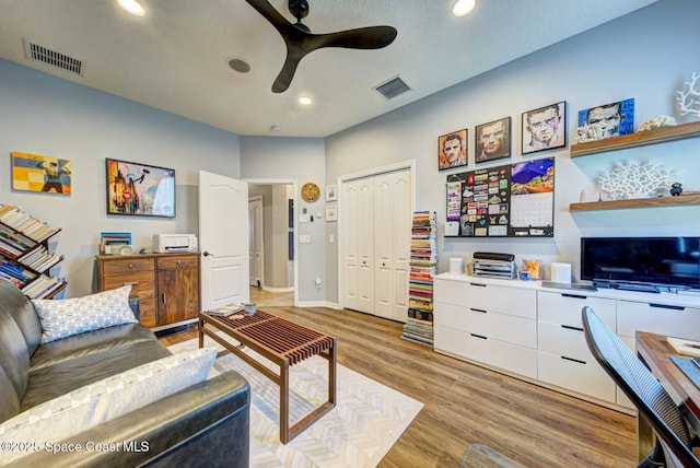 living area with light wood-type flooring, ceiling fan, visible vents, and recessed lighting