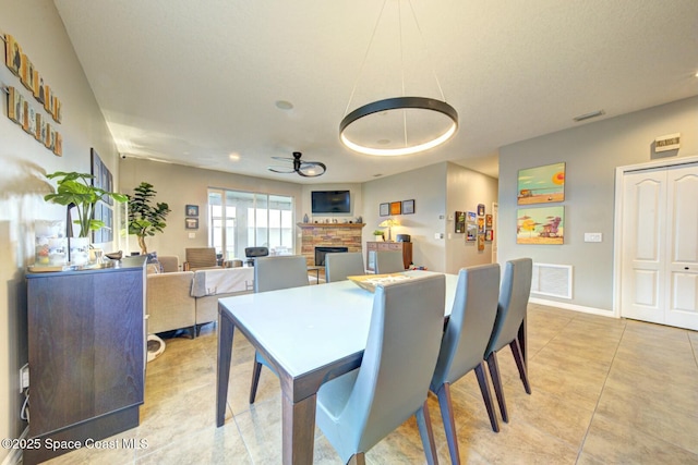 dining area with a fireplace, visible vents, a ceiling fan, and light tile patterned flooring