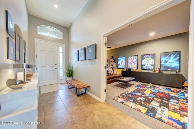 foyer entrance featuring a towering ceiling, light tile patterned floors, baseboards, and recessed lighting