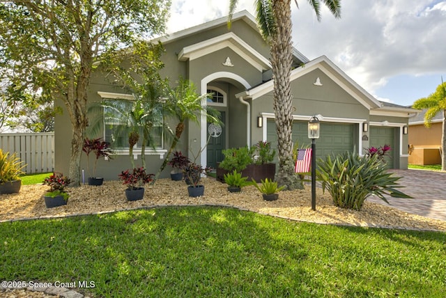 view of front of house with an attached garage, fence, decorative driveway, stucco siding, and a front yard