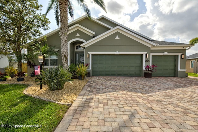 view of front of house with a garage, decorative driveway, and stucco siding