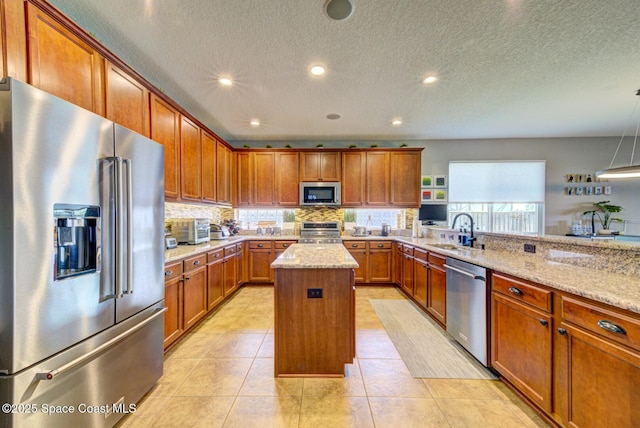 kitchen featuring appliances with stainless steel finishes, brown cabinetry, a sink, and a kitchen island