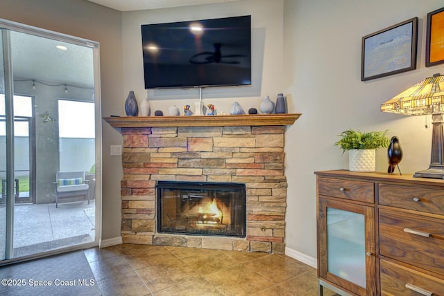 living area with a stone fireplace and baseboards