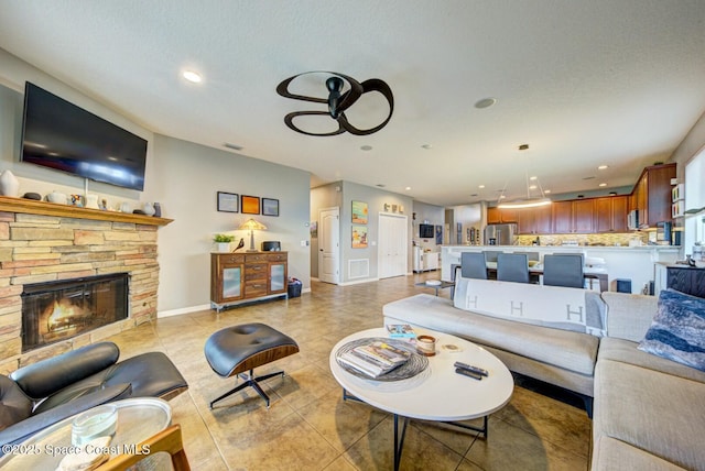 living room with a stone fireplace, light tile patterned flooring, recessed lighting, visible vents, and baseboards