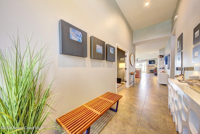 corridor featuring a towering ceiling and light tile patterned floors