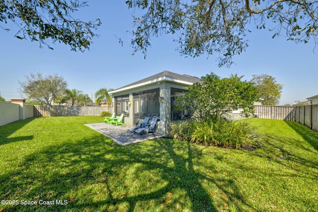 view of yard featuring a sunroom, a fenced backyard, and a patio