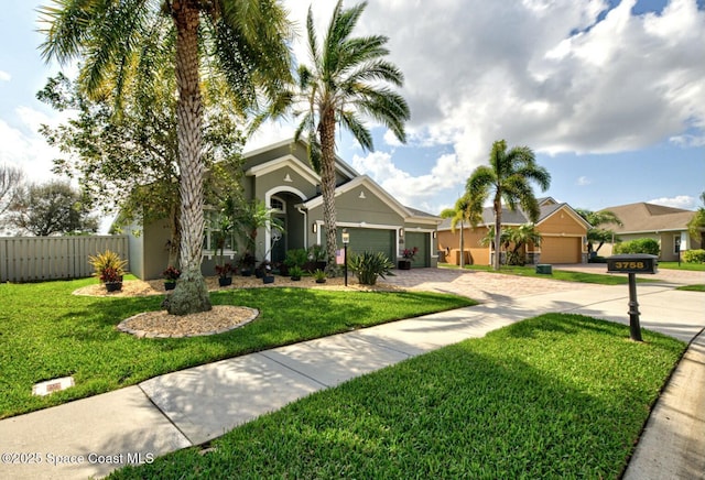 view of front of home with driveway, an attached garage, fence, a front yard, and stucco siding