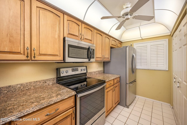 kitchen featuring light tile patterned floors, stone countertops, stainless steel appliances, a ceiling fan, and vaulted ceiling