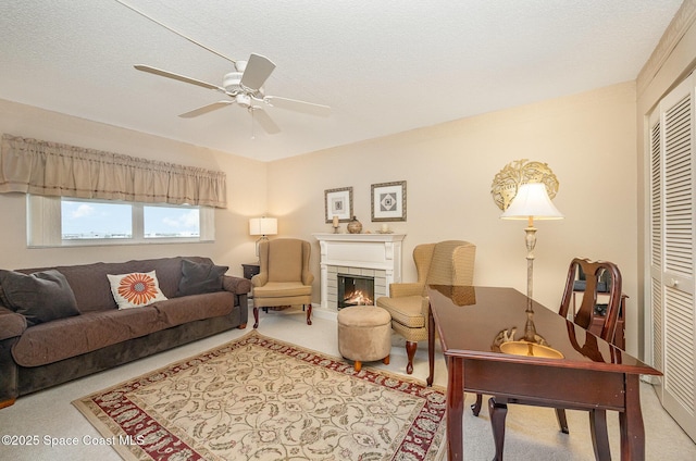 carpeted living area featuring a ceiling fan, a textured ceiling, and a tile fireplace