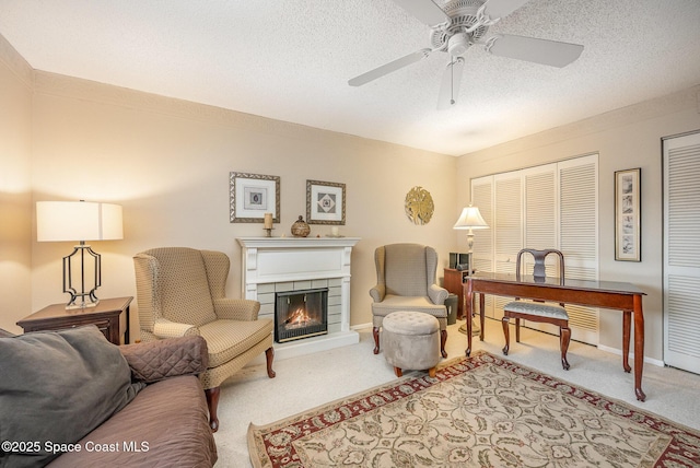 interior space with a textured ceiling, a lit fireplace, a ceiling fan, and baseboards