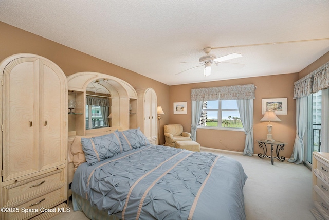 bedroom with ceiling fan, a textured ceiling, and light colored carpet