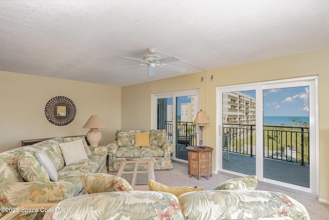 living room featuring carpet, a ceiling fan, and a textured ceiling