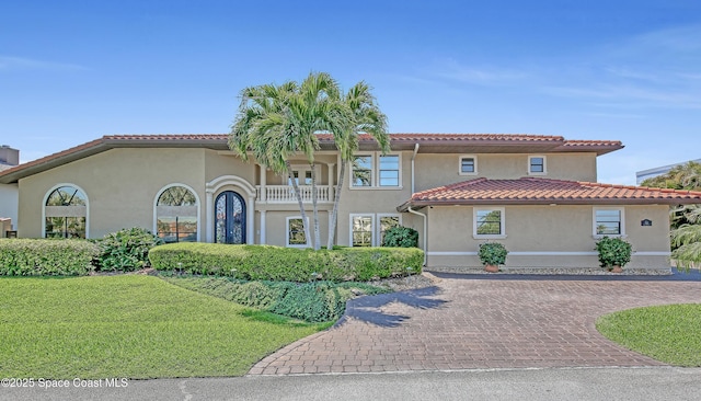 mediterranean / spanish-style home featuring stucco siding, a front lawn, and a tiled roof