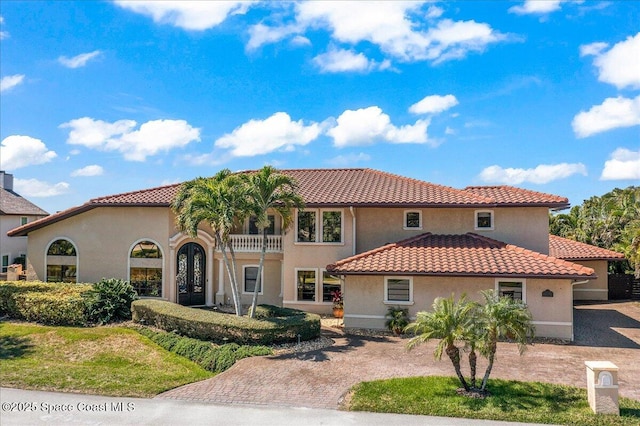 mediterranean / spanish house with decorative driveway, stucco siding, and a tiled roof