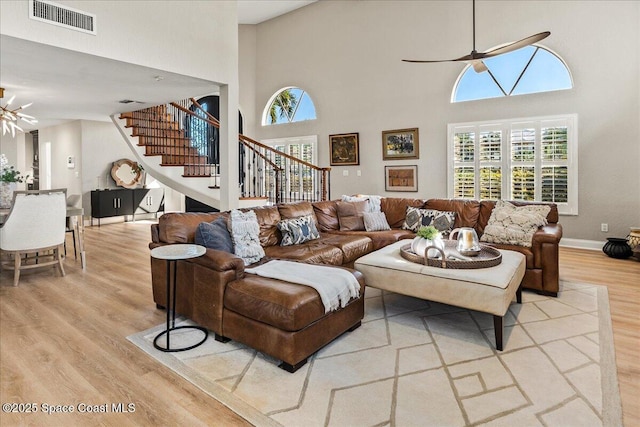 living room with visible vents, baseboards, stairway, wood finished floors, and a ceiling fan