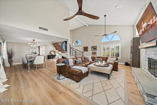 living room featuring visible vents, a stone fireplace, ceiling fan, and stairs