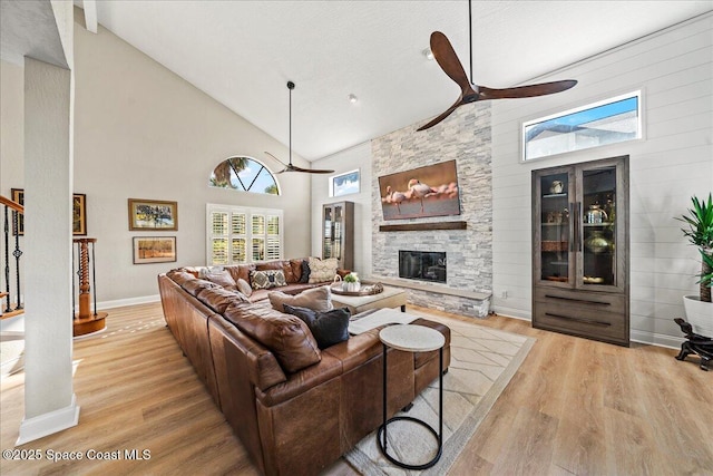 living room with a fireplace, high vaulted ceiling, ceiling fan, and wood finished floors