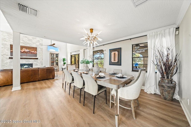 dining area featuring visible vents, a textured ceiling, wood finished floors, a fireplace, and baseboards