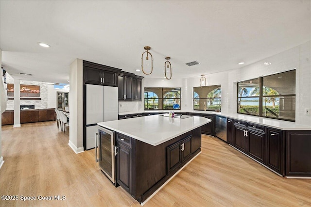 kitchen with visible vents, beverage cooler, light countertops, light wood-style floors, and refrigerator