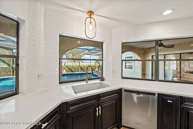 kitchen with stainless steel dishwasher, light countertops, hanging light fixtures, and a sink