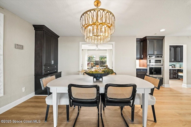 dining room with a notable chandelier, a textured ceiling, baseboards, and light wood-style floors