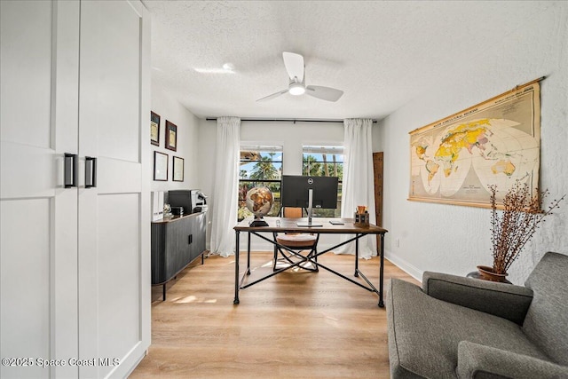 office area featuring light wood finished floors, baseboards, a textured ceiling, and a ceiling fan