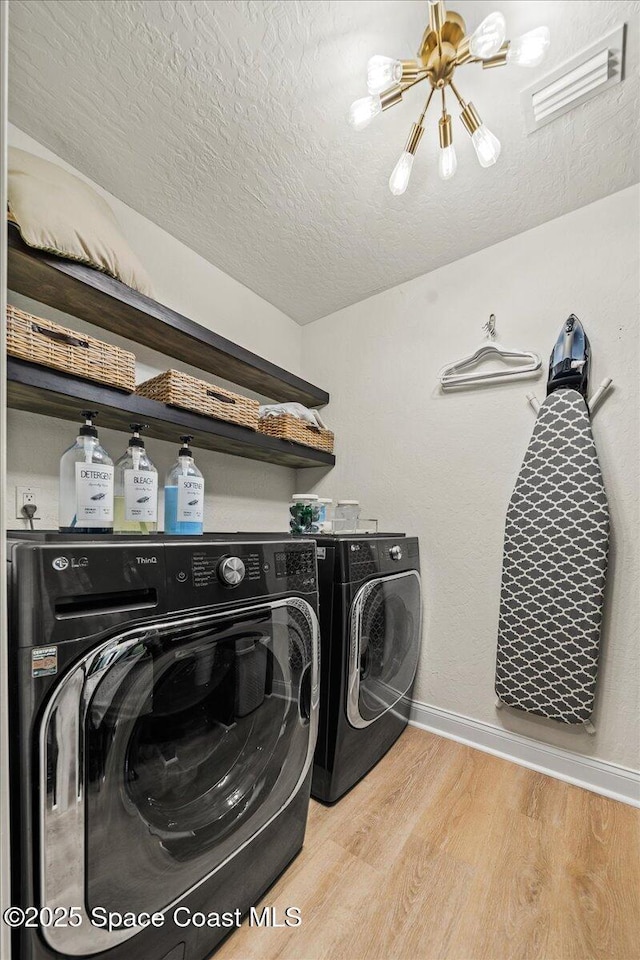 laundry room with baseboards, laundry area, light wood-style floors, washer and dryer, and a textured ceiling