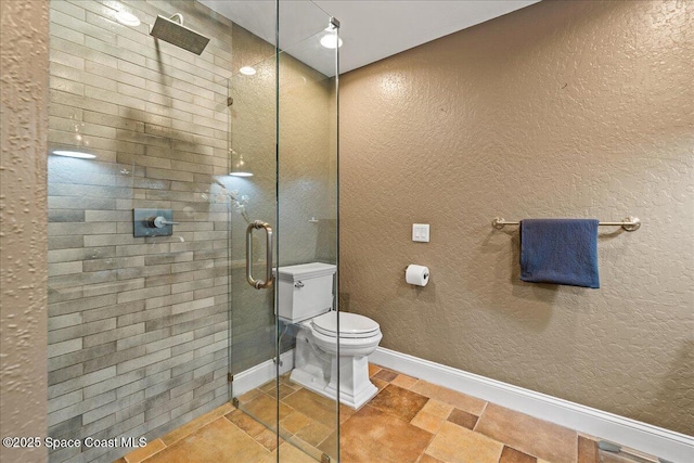 bathroom with a shower stall, toilet, a textured wall, and baseboards