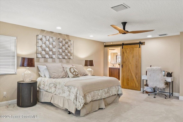 carpeted bedroom featuring visible vents, a barn door, and a textured ceiling