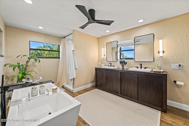 full bathroom with wood finished floors, a textured wall, and a sink