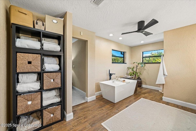 office area featuring visible vents, a textured ceiling, wood finished floors, baseboards, and ceiling fan