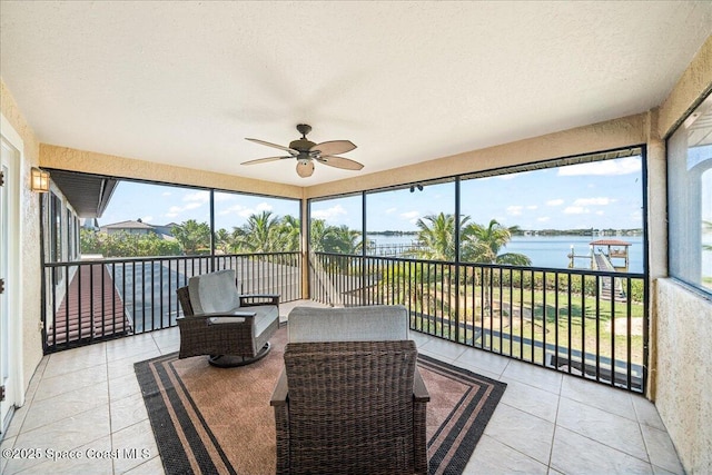 sunroom / solarium with a ceiling fan and a water view