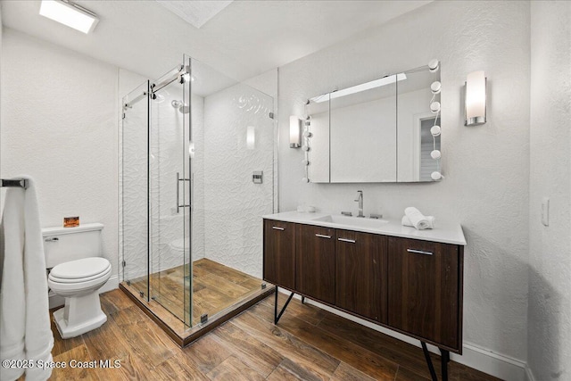 full bath featuring vanity, wood finished floors, a shower stall, and toilet