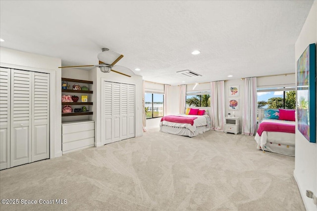 bedroom with recessed lighting, visible vents, two closets, and carpet flooring