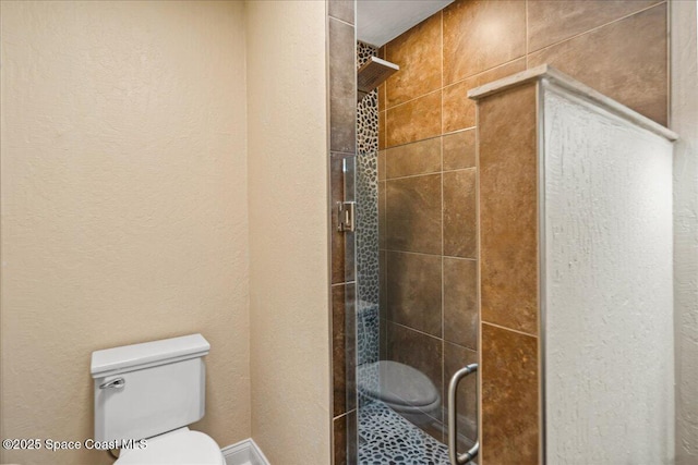 bathroom featuring a shower stall, toilet, and a textured wall