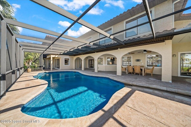 pool with glass enclosure, a patio area, and a ceiling fan