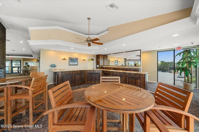 dining room with visible vents, ornamental molding, a ceiling fan, a bar, and baseboards