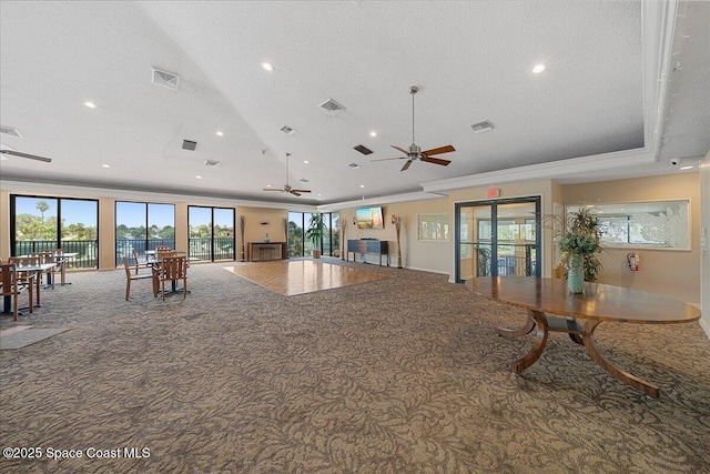 unfurnished living room featuring carpet, a raised ceiling, a ceiling fan, and visible vents