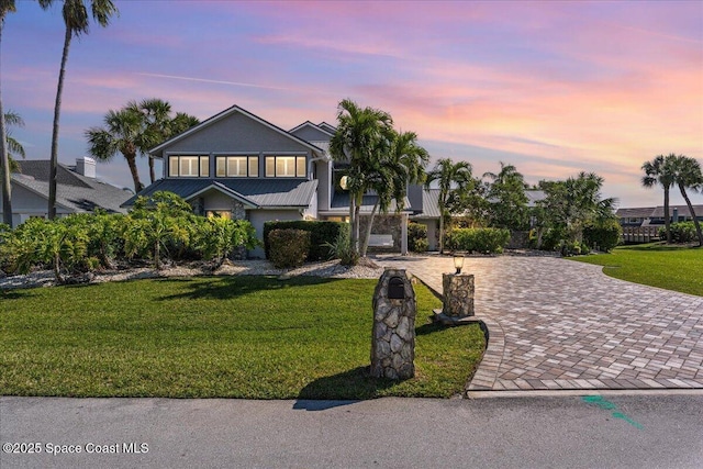 view of front of home featuring decorative driveway, a front lawn, and stucco siding