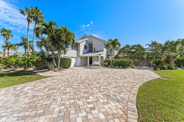 view of front of property with decorative driveway, a front lawn, and stucco siding